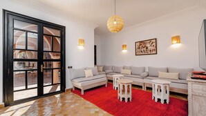 Un salon moderne avec un tapis rouge, un canapé d’angle, une petite table blanche et un luminaire suspendu.