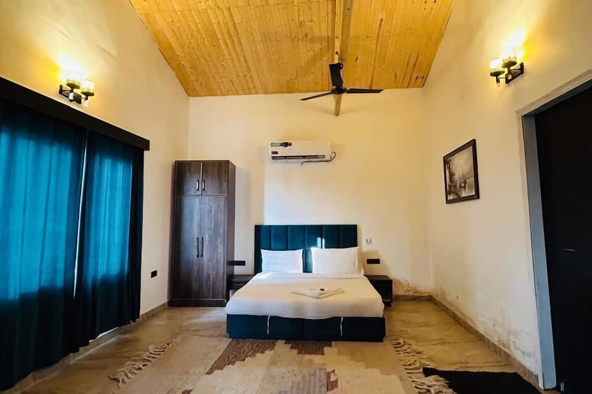 Une chambre avec un plafond en bois, un lit doté d’une tête de lit, un appareil de climatisation et une porte.