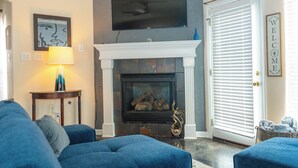 A living room with a fireplace, a television mounted above it, and a blue sofa.