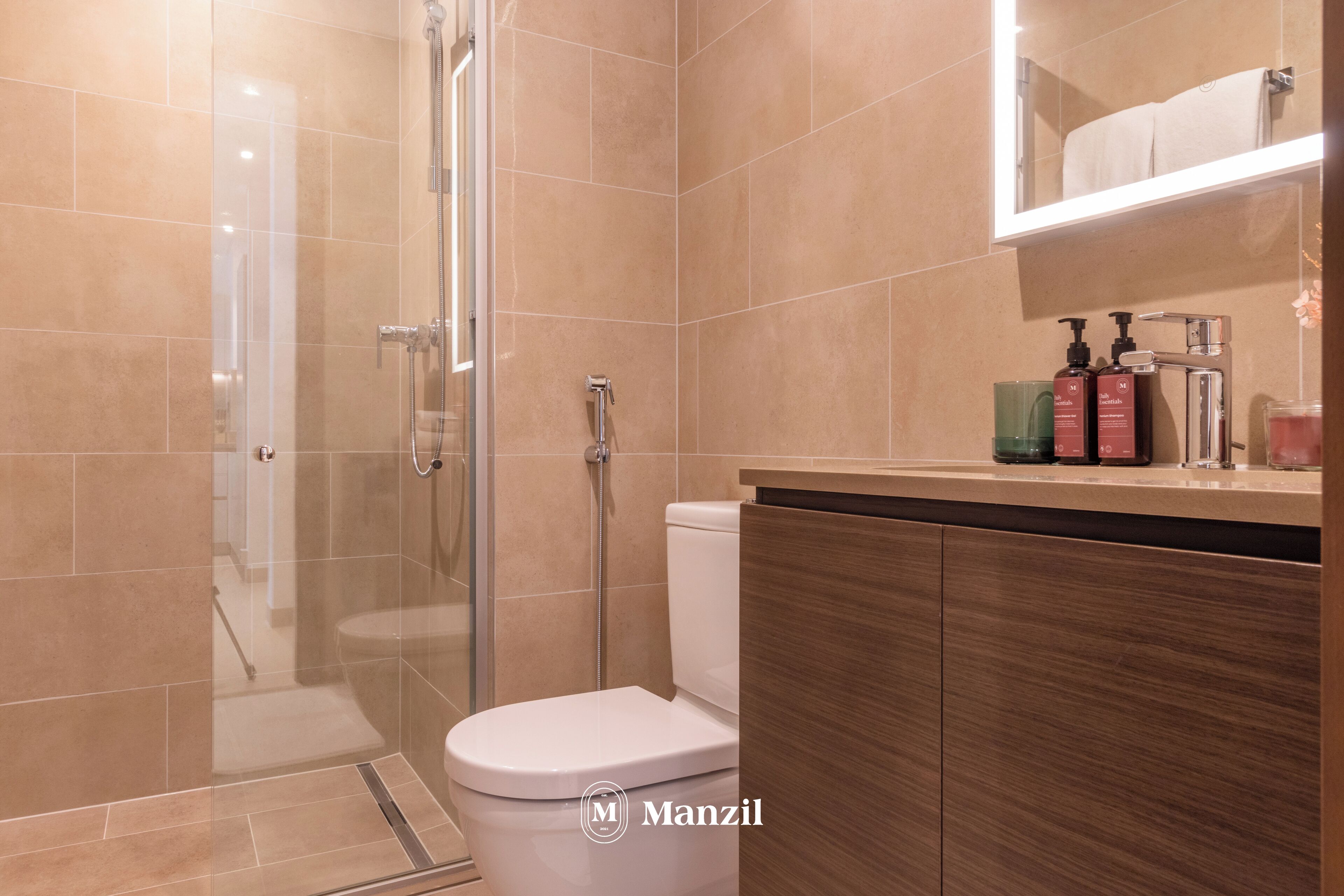 A modern bathroom with a glass shower enclosure, a white toilet, and a wooden vanity with toiletries.