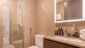Une salle de bain moderne avec une douche à parois de verre, des toilettes blanches et un meuble-lavabo avec un miroir.