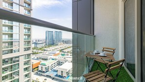 Un balcon avec une table et des chaises, une vue sur le paysage urbain et un immeuble doté de balcons.