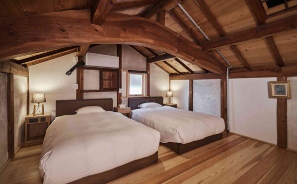 Een gezellig slaapkamer op zolder met twee bedden, houten balken en een schuine kap.
