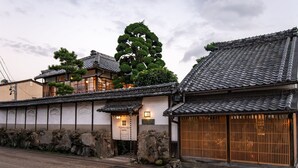 Ein traditionelles japanisches Hotel mit mehreren Gebäuden, Steinmauern und Ziegeldächern.