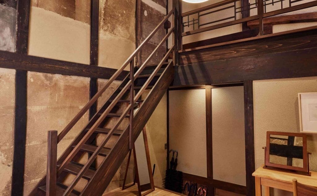 A staircase with a wooden handrail leading to a second floor.