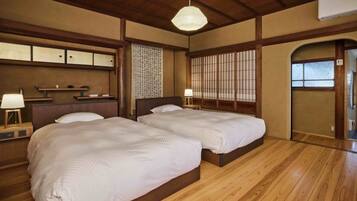 Una habitación tradicional japonesa con dos camas, suelo de madera y puertas correderas.