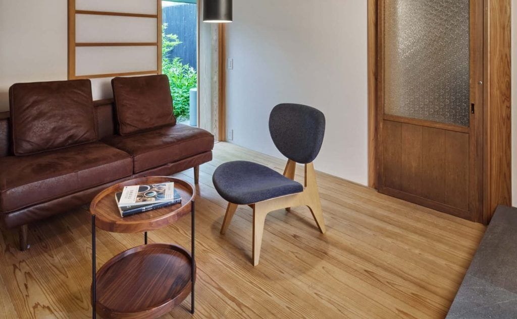 A modern living room with a brown leather sofa, a blue chair, and a small wooden table.