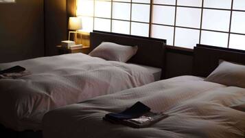 A hotel room with two beds, a nightstand with a lamp, and a window with a grid pattern.