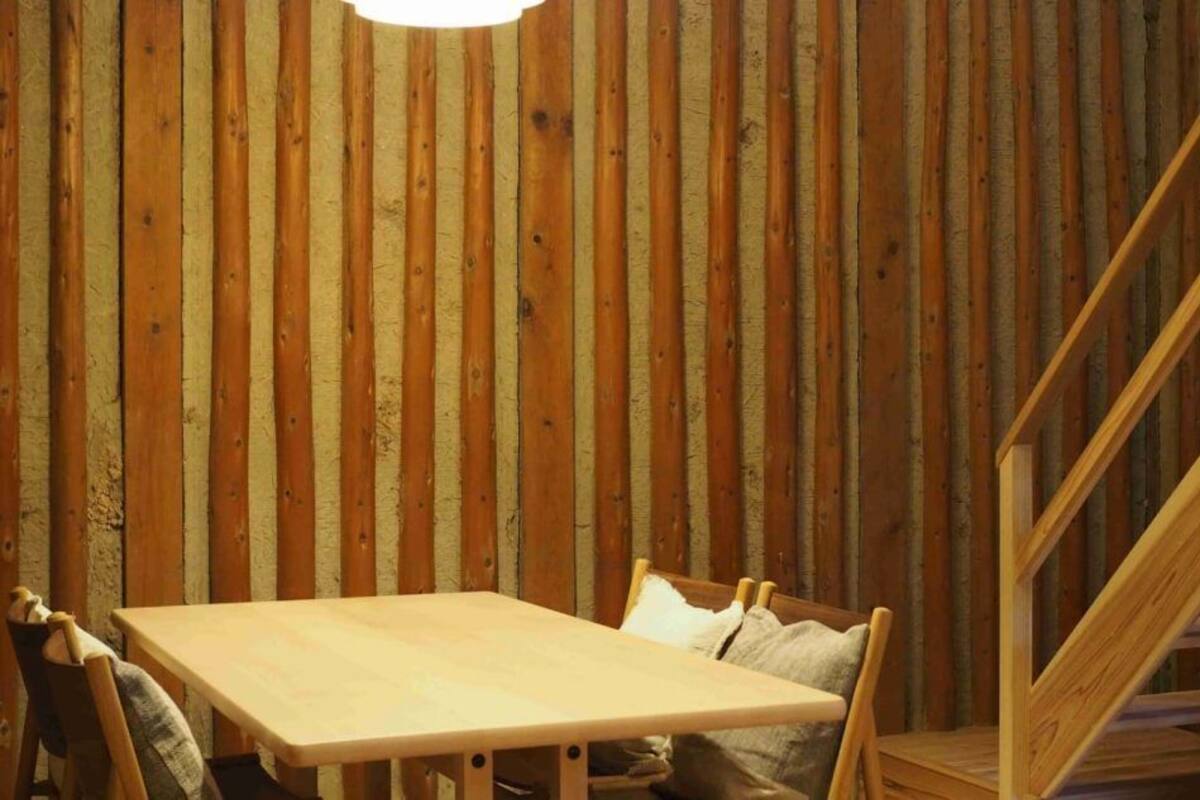 Une pièce avec un mur recouvert de lambris en bois, une table en bois et une chaise.