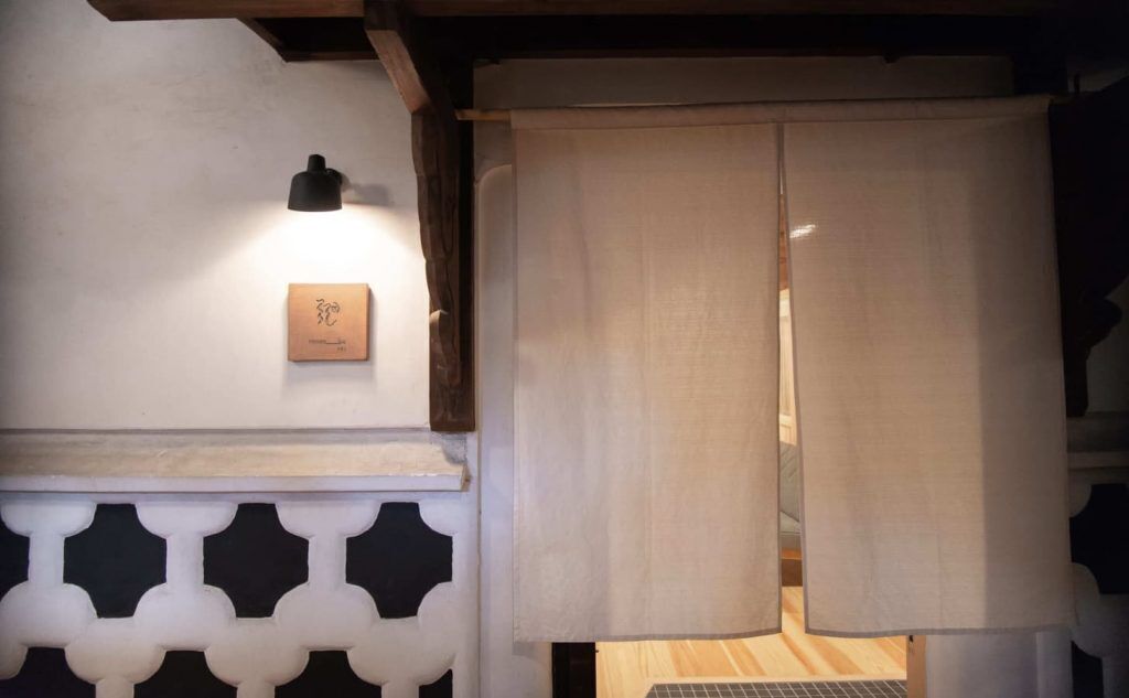 A traditional Japanese room with sliding doors, a wooden beam ceiling, and a small plaque on the wall.