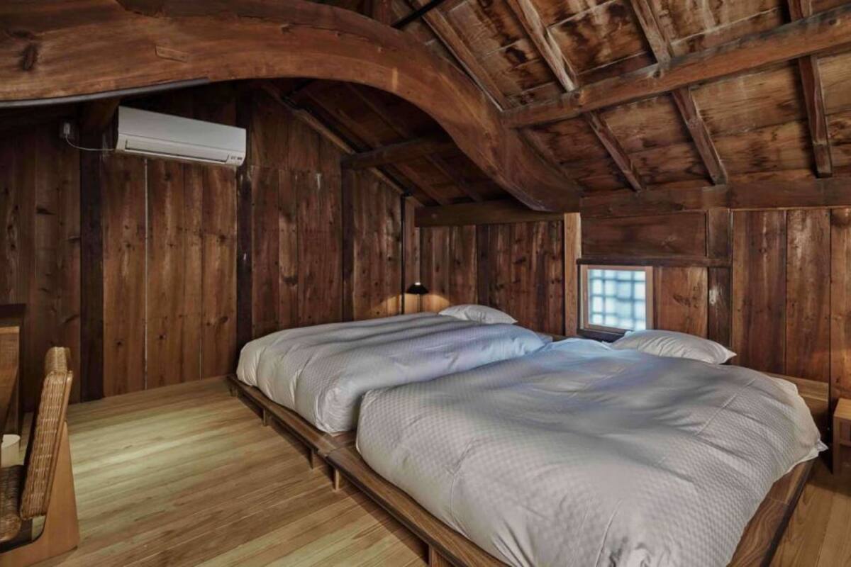 Une chambre dans un chalet en bois, avec deux lits, une fenêtre et un appareil de climatisation.