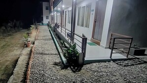 A building with a paved walkway, potted plants, and a metal railing. - River Beach Resort (Dhussa)