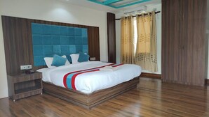 A bedroom with a large bed, wooden flooring, a blue headboard, and a wardrobe. - River Beach Resort (Dhussa)