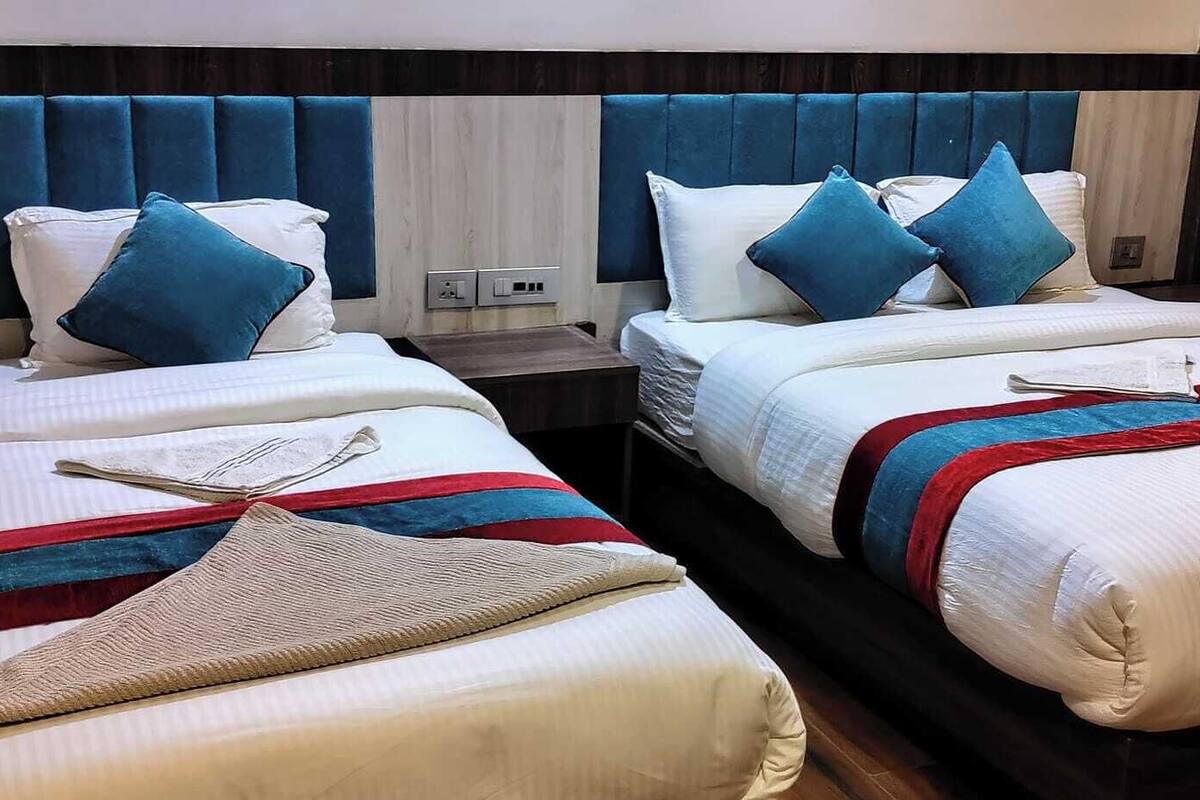 Two double beds with headboards, white bedding, blue pillows, and red and blue striped blankets.