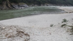 A sandy beach with a river and forested hills in the background. - River Beach Resort (Dhussa)