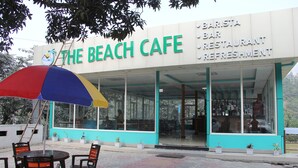 A beach cafe with outdoor seating and a sign advertising barista, bar, restaurant, and refreshment services. - River Beach Resort (Dhussa)