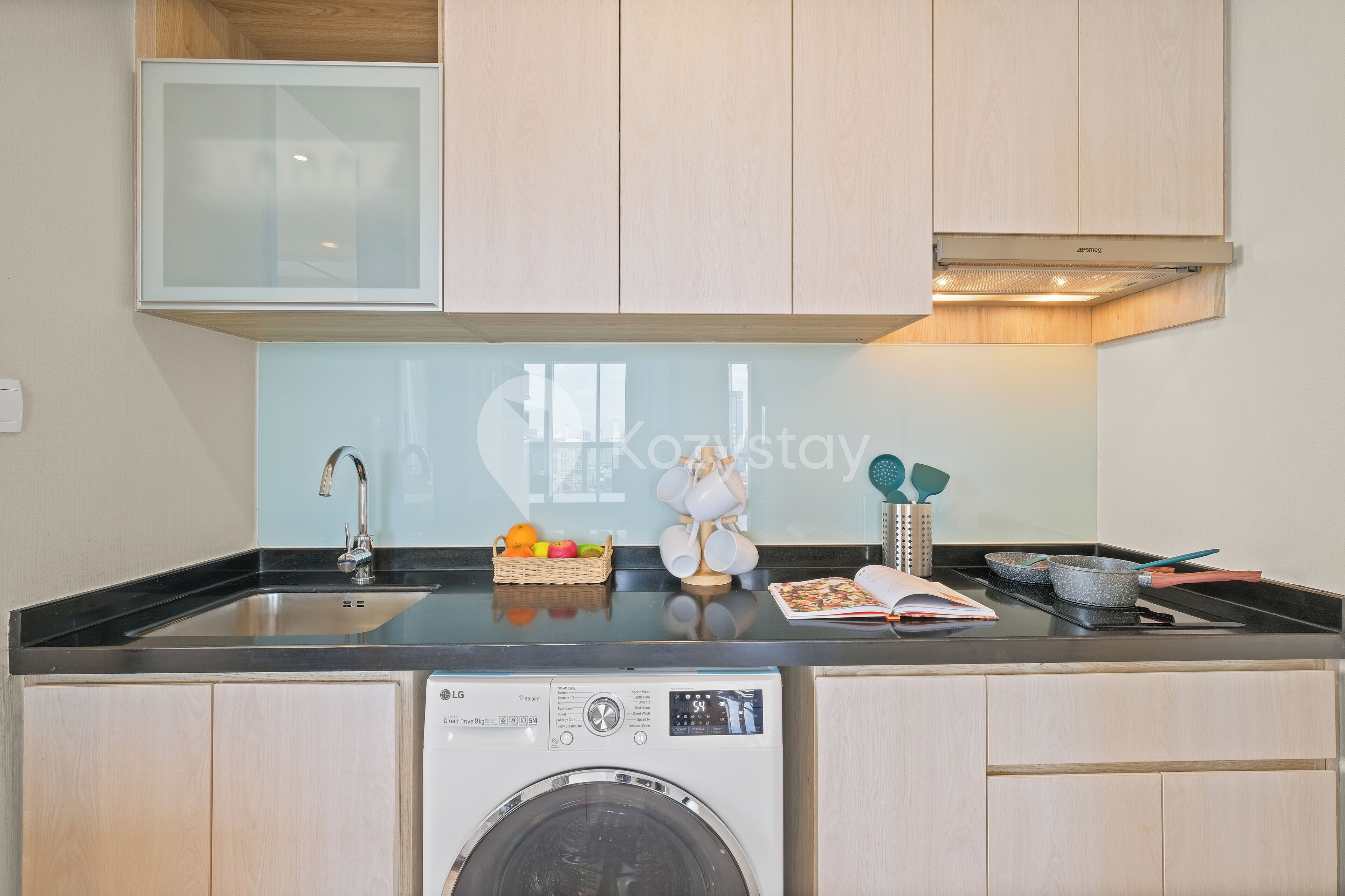 A compact kitchen with a washing machine, a sink, and a small countertop.