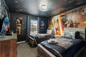 A bedroom with two beds, Star Wars themed decor, and a galaxy-themed ceiling.