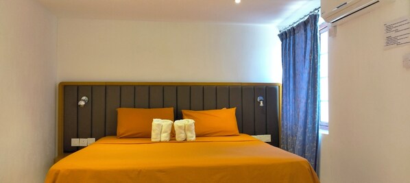 A hotel room with a bed, two pillows, and a window with curtains.