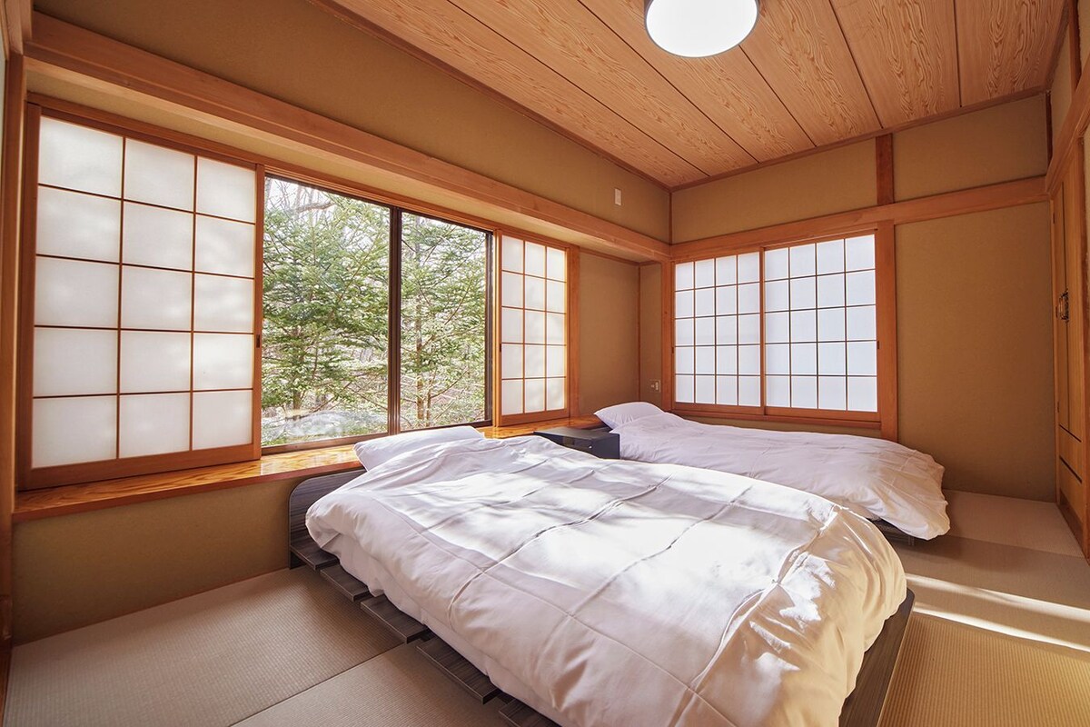 Una habitación tradicional japonesa con suelo de tatami, techo bajo y puertas correderas shoji.