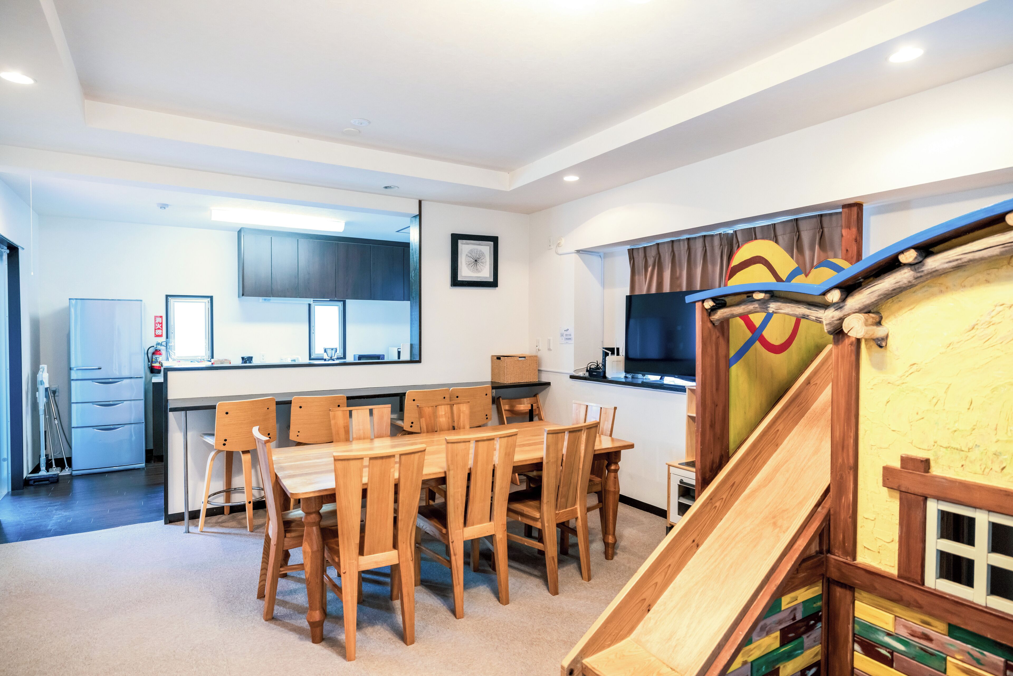 Una cocina moderna con comedor, sillas de madera, una isla de cocina y una zona de juegos infantiles con tobogán.
