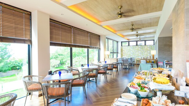 A spacious dining area with wooden flooring, wicker chairs, and a buffet table with various food items. - SCALLOP BEACH CONDMINIUM (Onna)
