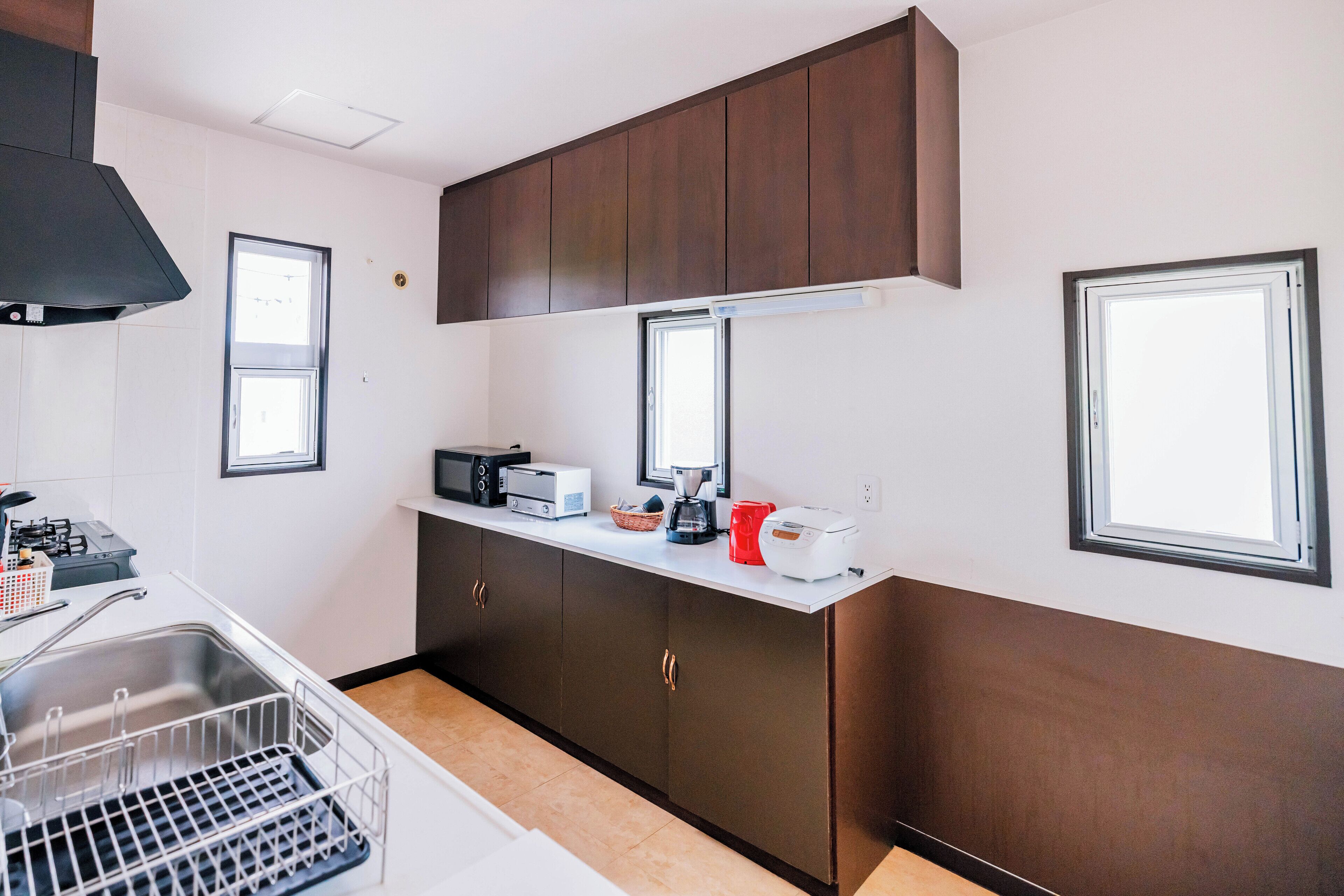 A compact kitchen with a microwave, toaster, and coffee maker on the counter, a sink, and cabinets with gold handles.