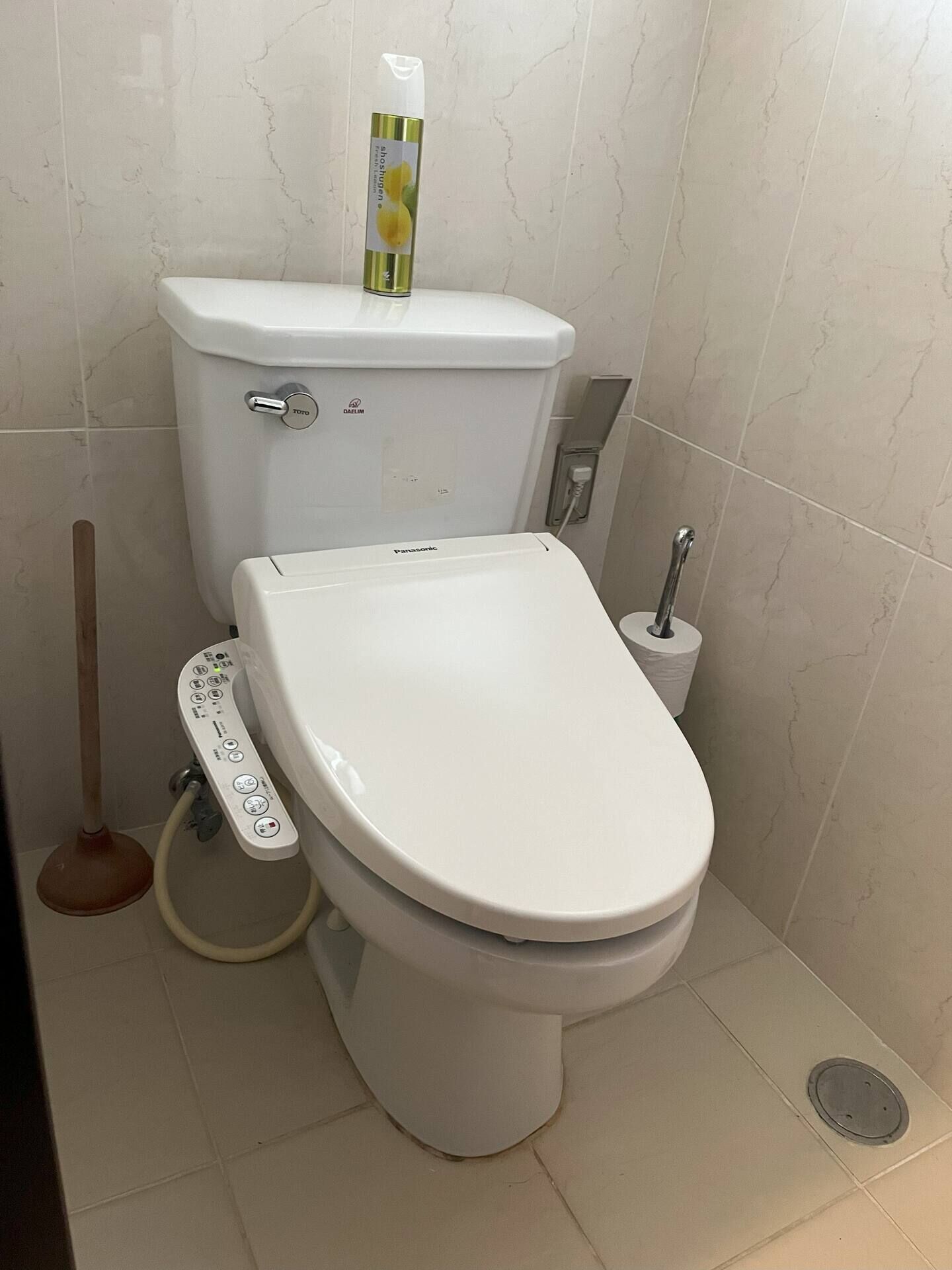 A modern toilet with a control panel, a toilet paper holder, and a bidet attachment.