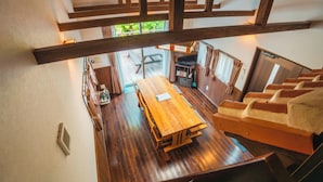 A wooden dining table in a room with a view of a garden through a window. - SCALLOP BEACH CONDMINIUM (Onna)