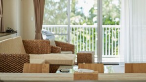 A room with a ceiling fan, a sofa, a table, and a view of a balcony. - SCALLOP BEACH CONDMINIUM (Onna)
