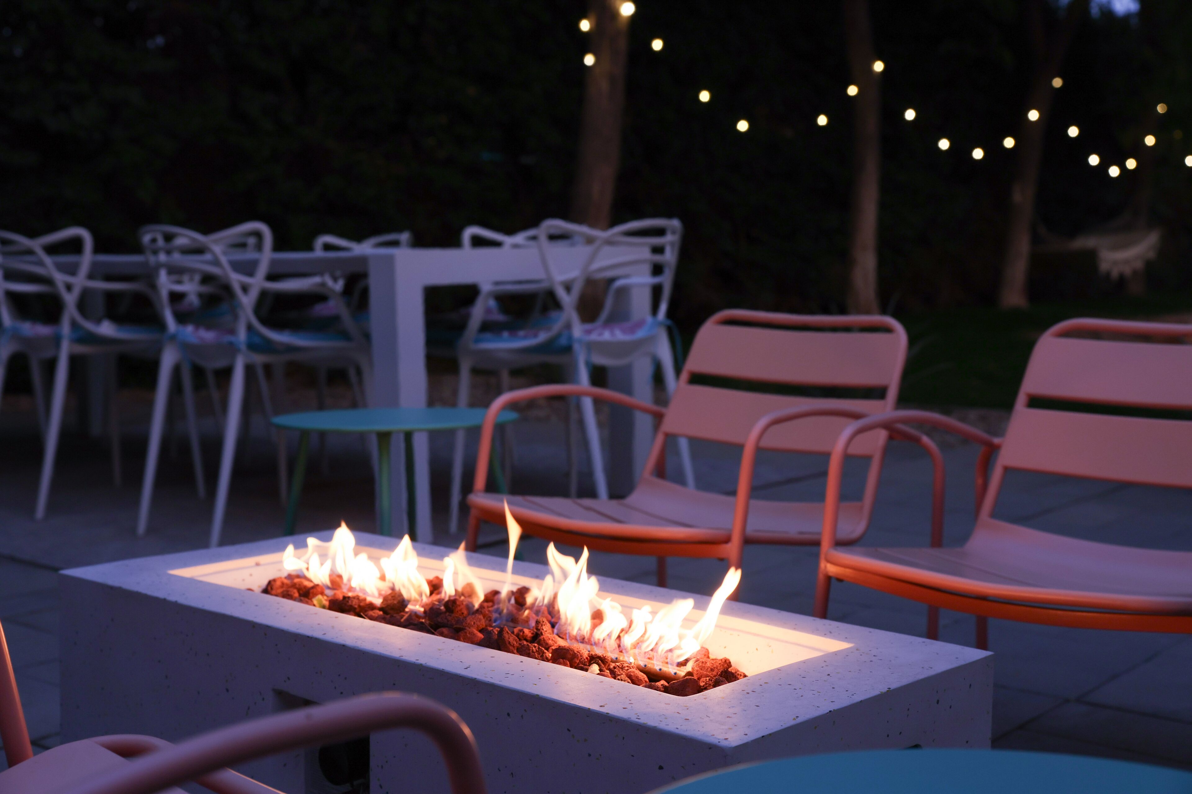An outdoor seating area with a fire feature, chairs, and tables.