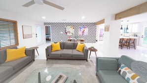 En moderne stue med en grå sofa, et glasbord og en loftventilator.