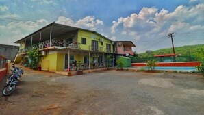 A two-story building with a balcony and a covered area. - Lingmala Greens (Mahabaleshwar)