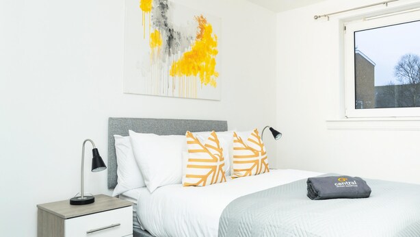 A modern bedroom with a bed, bedside tables, and a window. - Kinnaird by Central Serviced Apartments (Dundee)