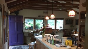 Une cuisine avec un plafond en bois, une porte violette et un coin bar avec des tabourets.