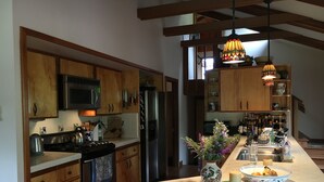 Une cuisine moderne avec des meubles en bois, des appareils électroménagers en acier inoxydable et un îlot central agrémenté d’un vase de fleurs.