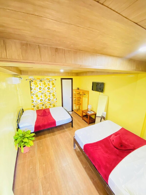 A room with two beds, a wooden ceiling, a small table with a lamp, and a potted plant. - Ramfels Paradise Resort (Surallah)