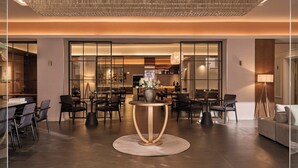 A modern lobby with a central round table, seating arrangements, and a large chandelier.