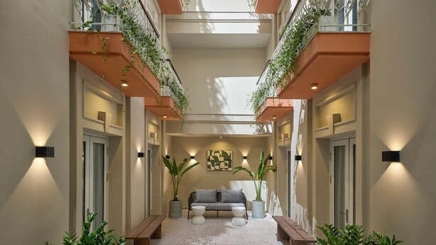 A corridor with a sofa, benches, and potted plants.