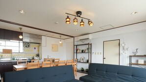 A modern living room with dark blue sofas, a dining area with wooden chairs, and a kitchen in the background. - Room 701 Gureisumukojima (Tokyo)
