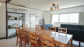 A dining area with a wooden table and chairs, a black sofa, and a window with curtains. - Room 701 Gureisumukojima (Tokyo)