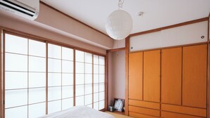 A traditional Japanese-style room with tatami flooring, a sliding wooden door, and a large window with a grid pattern. - Room 701 Gureisumukojima (Tokyo)