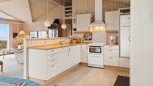 Ett modernt kök med träskåp, en inbyggd ugn och ett kylskåp.