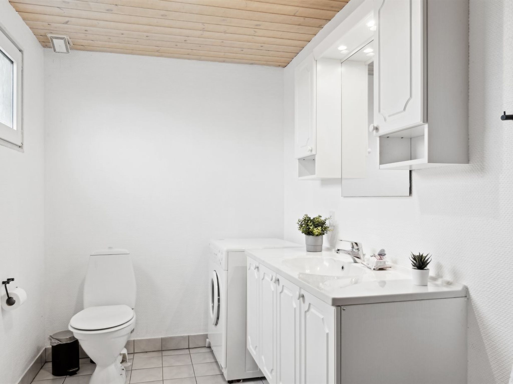 A modern bathroom with a toilet, washing machine, and sink area.