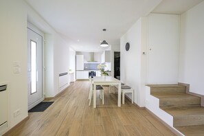 Eine moderne Küche mit weißen Schränken, ein Essbereich mit Tisch und Stühlen sowie eine Treppe mit Holzstufen.