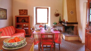 Un comedor con una mesa preparada para cuatro personas, una chimenea, un ventanal y un sofá.
