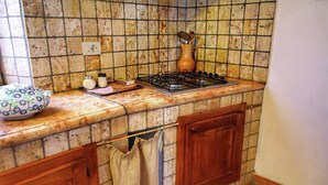Una cocina con salpicadero de azulejos, estufa, gabinete de madera y un paño colgado.