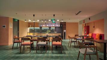 A modern dining area with a central island, multiple seating arrangements, and a kitchen in the background.