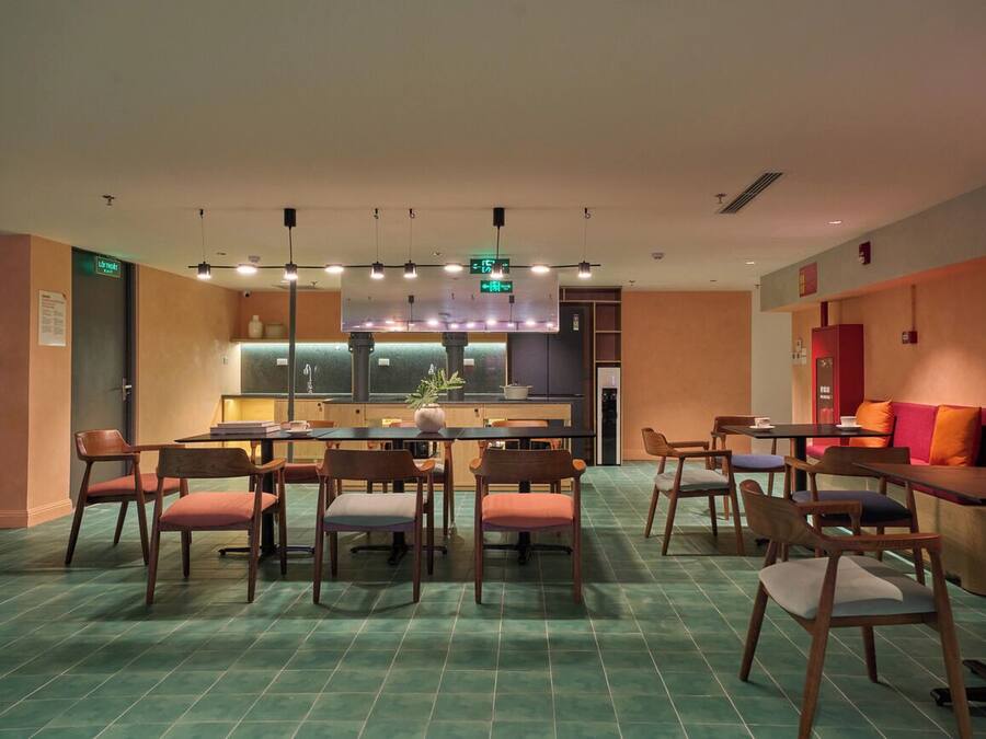 A modern dining area with a central island, multiple seating arrangements, and a kitchen in the background.