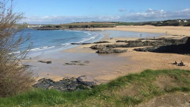 A coastal beach with rocky outcrops, clear skies, and distant buildings. - SeaSalt -Low cost accommodation, Harlyn Sands (Padstow)
